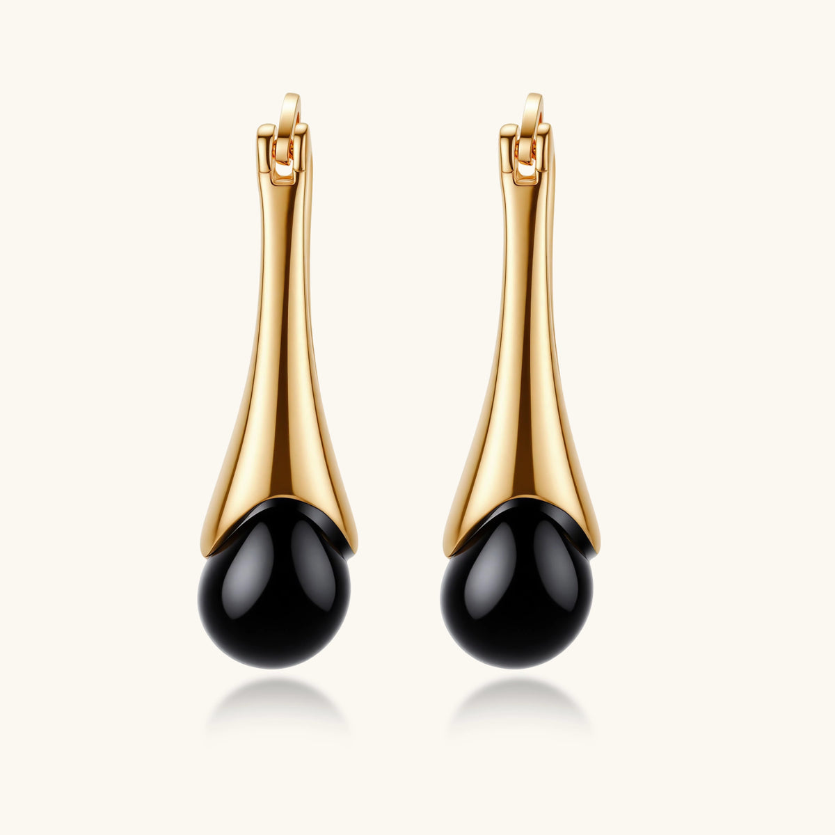 Gold-plated drop earrings featuring black agate stones with hoop closure on white background, showing elegant teardrop design.