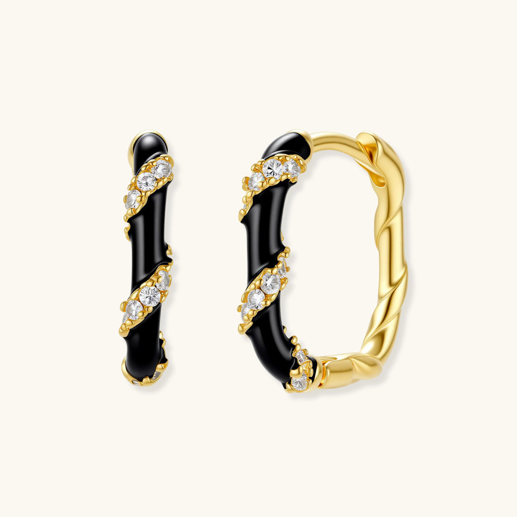 Small gold-plated hoop earrings with black enamel stripes and cubic zirconia crystals on white background.