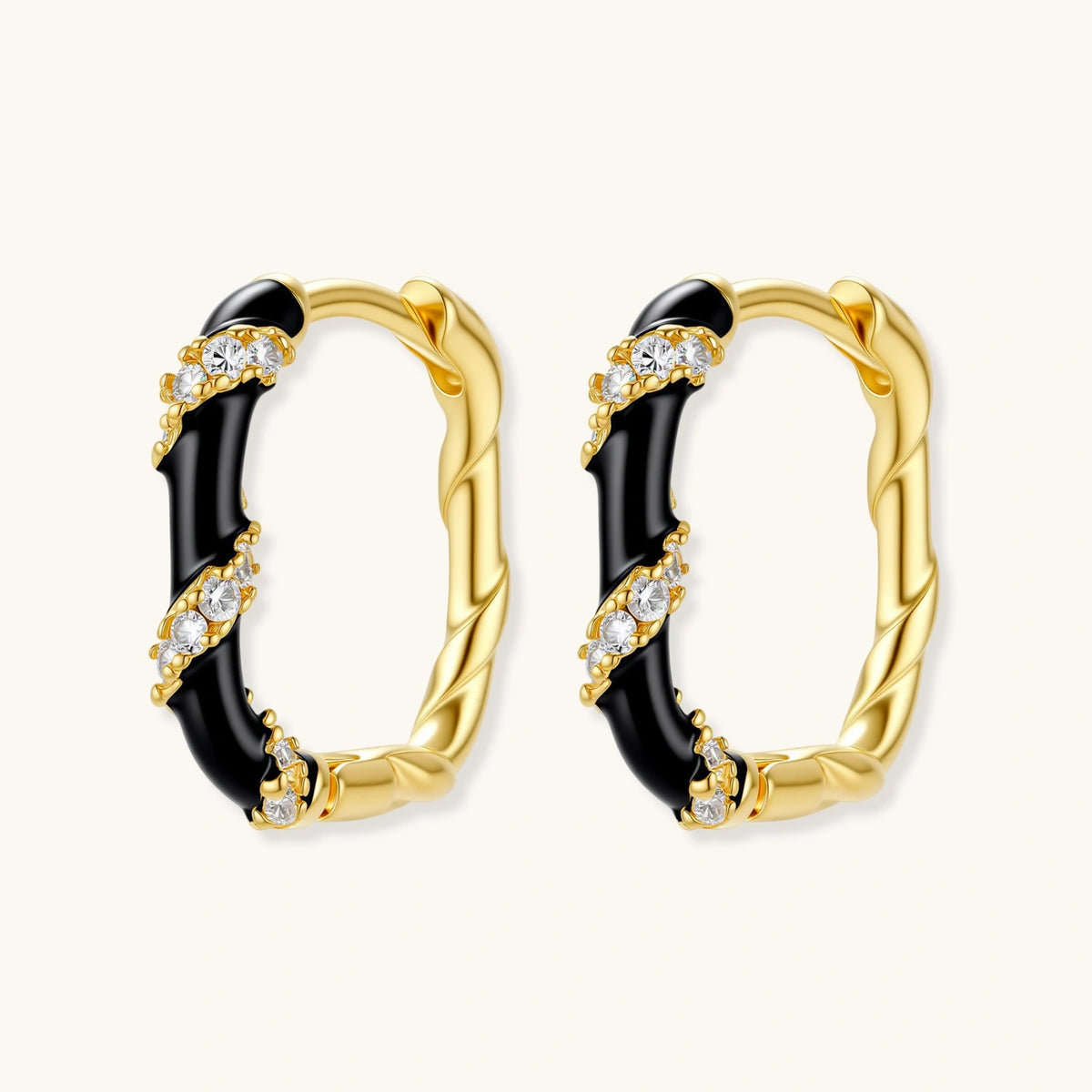 Small gold-plated hoop earrings with black enamel stripes and cubic zirconia crystals on white background.