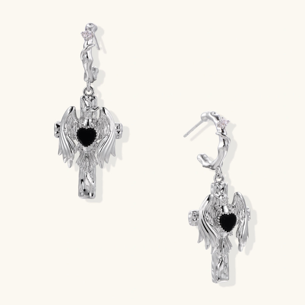 Silver-toned drop earrings with angel wings framing a black heart-shaped stone, white gold plated brass with S925 posts