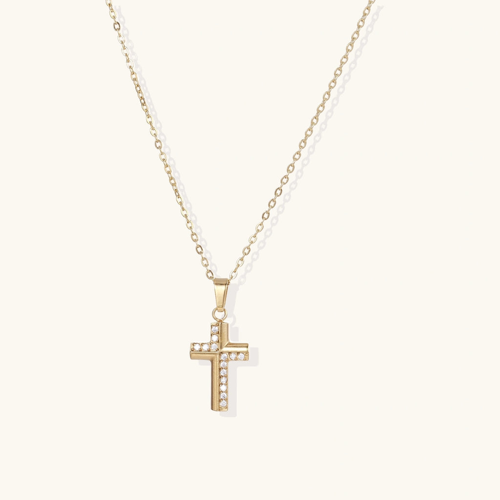 Gold-plated stainless steel cross necklace with crystal embellishments on adjustable chain against light background.