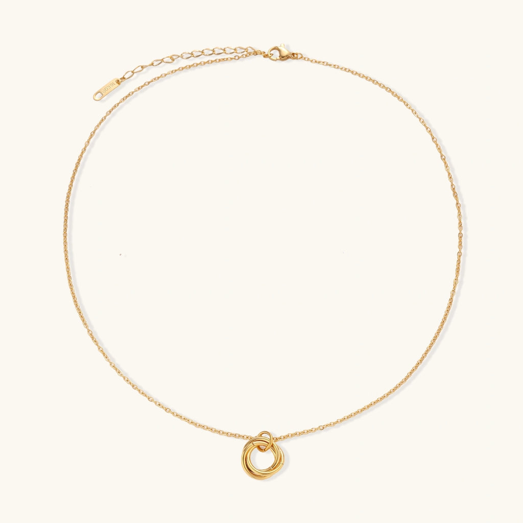 Delicate gold-plated necklace with three interlocking circle rings forming a minimalist knot pendant on cream background