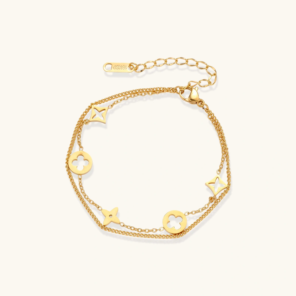 Double-layer gold-plated bracelet with quatrefoil and star charms on cream background, 18K gold finish.