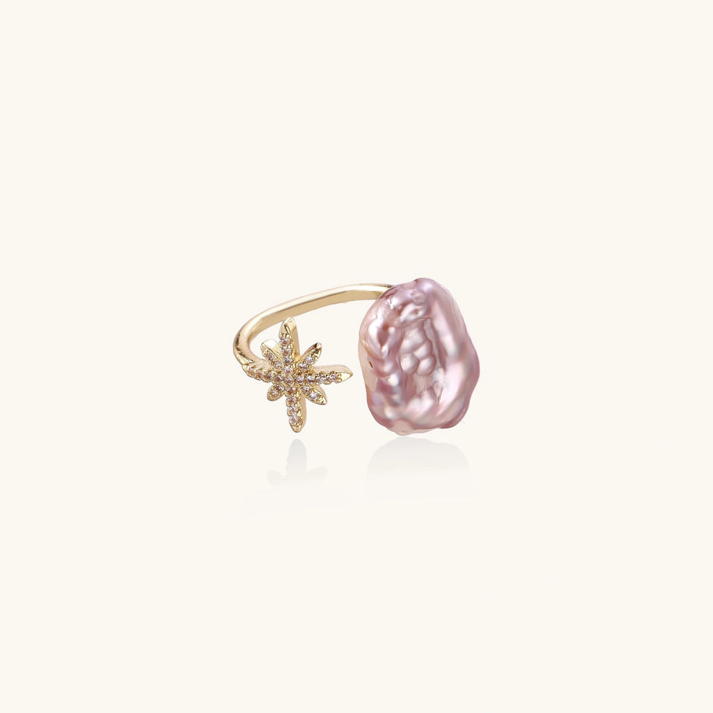 Adjustable gold ring with pink baroque freshwater pearl and crystal-studded star charm on white background